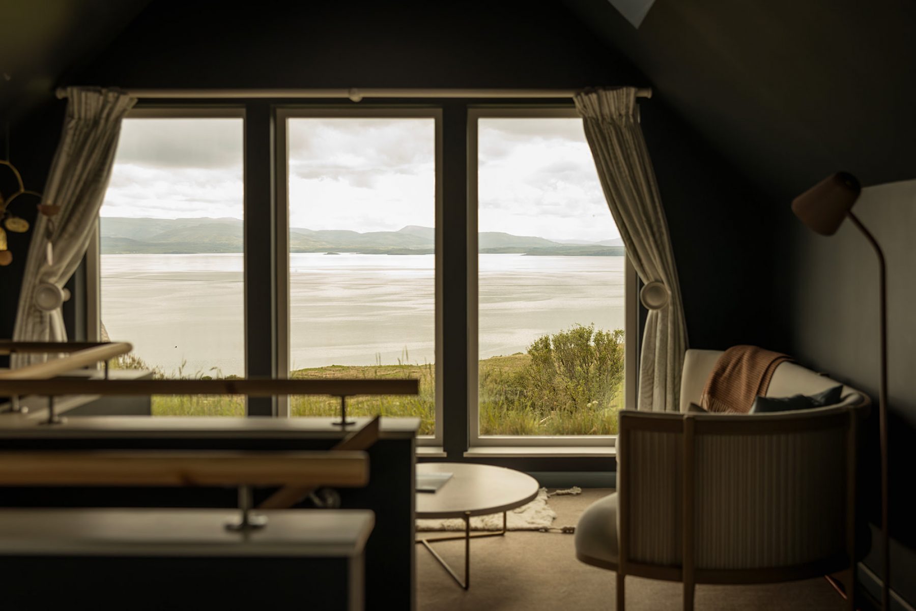 From inside the bedroom at the historic blackhouse holiday cottage, Mint Croft, Skye. A sofa by a large window with sea views across Loch Snizort and to the Trotternish peninsual.