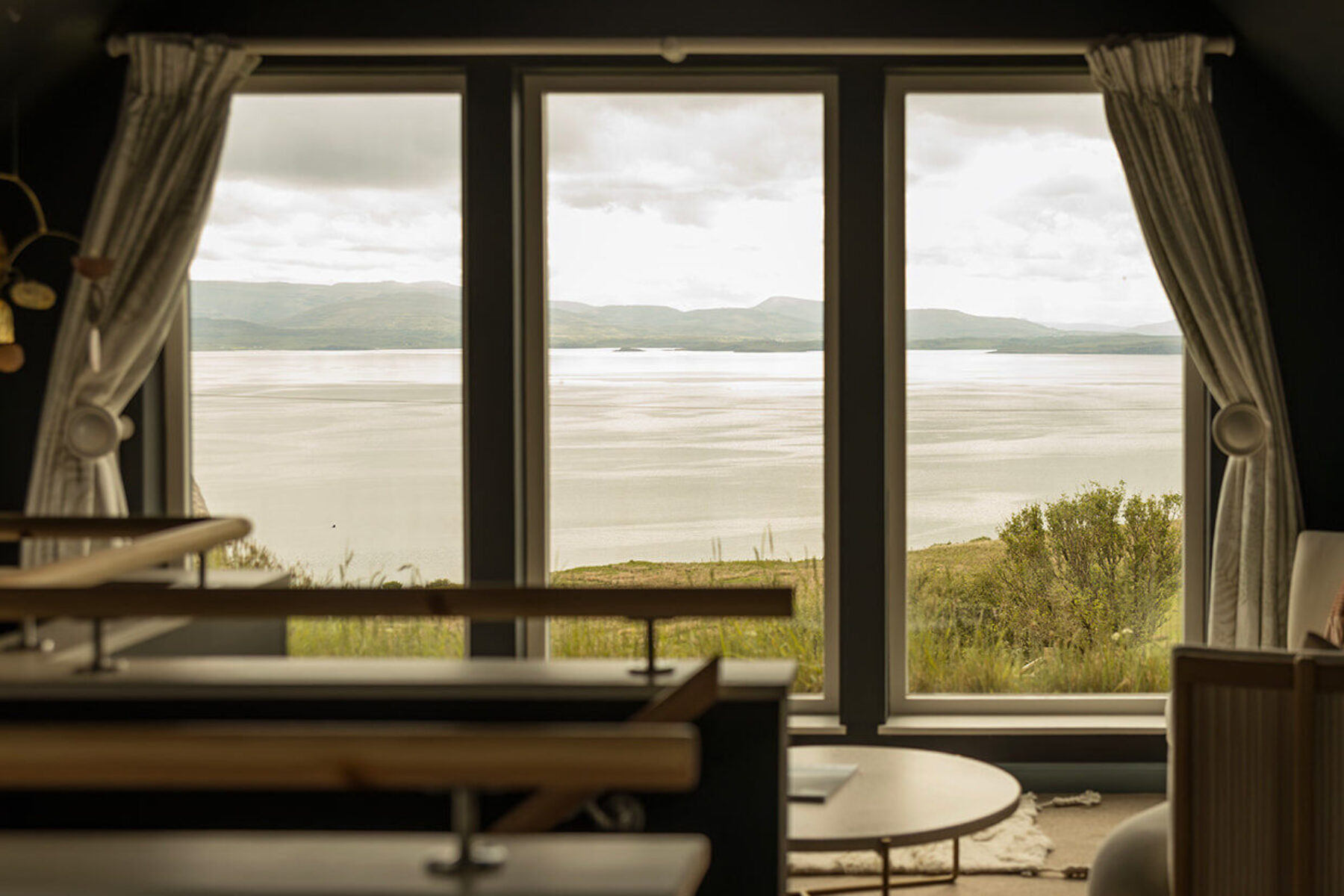 From inside the bedroom at the historic blackhouse holiday cottage, Mint Croft, Skye. A sofa by a large window with sea views across Loch Snizort and to the Trotternish peninsual.