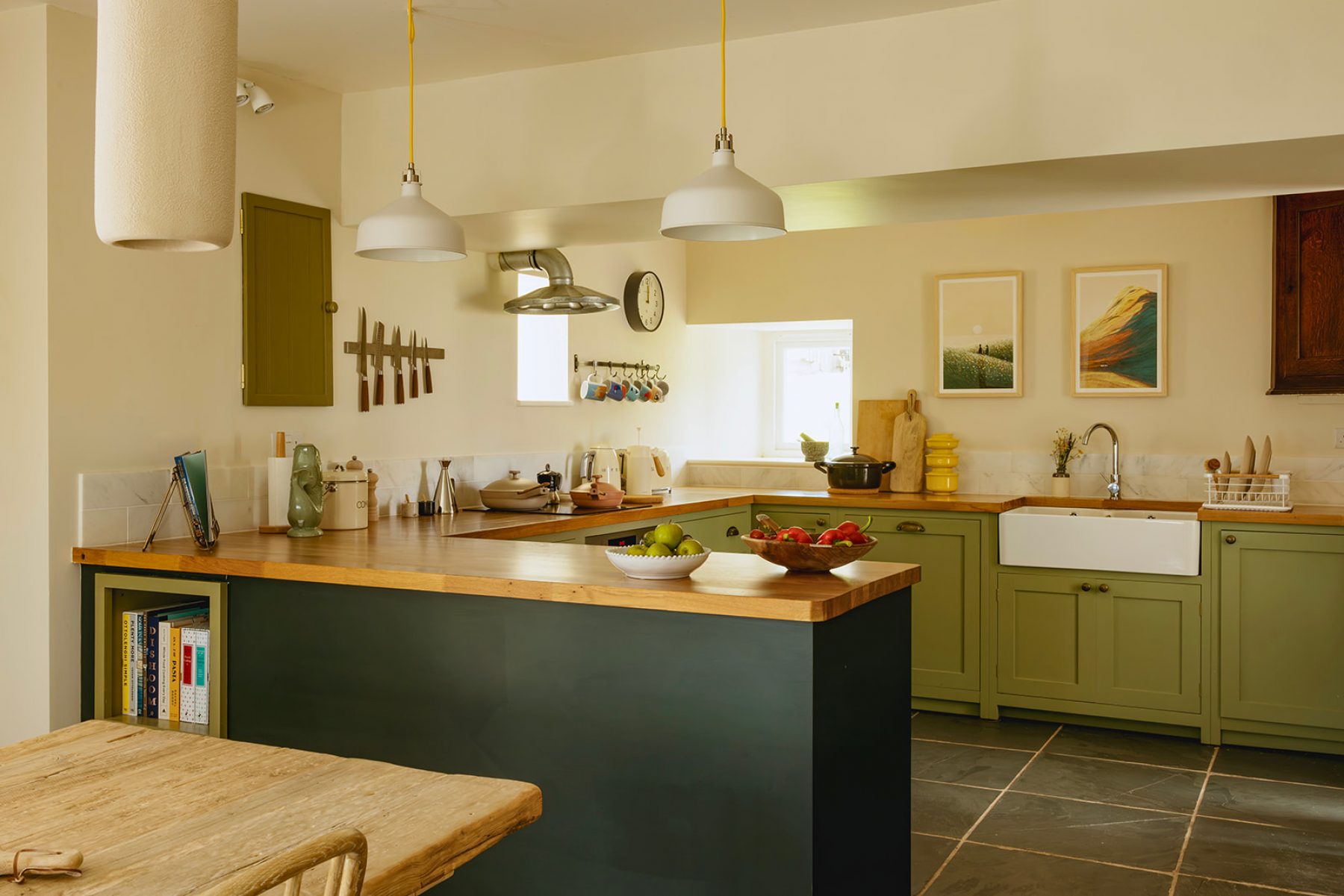 Croft House kitchen at Mint Croft, Isle of Skye, Scotland. Handmade wooden green-painted kitchen with wooden worktops, flagstone floor. Industrial style pendant lamps.