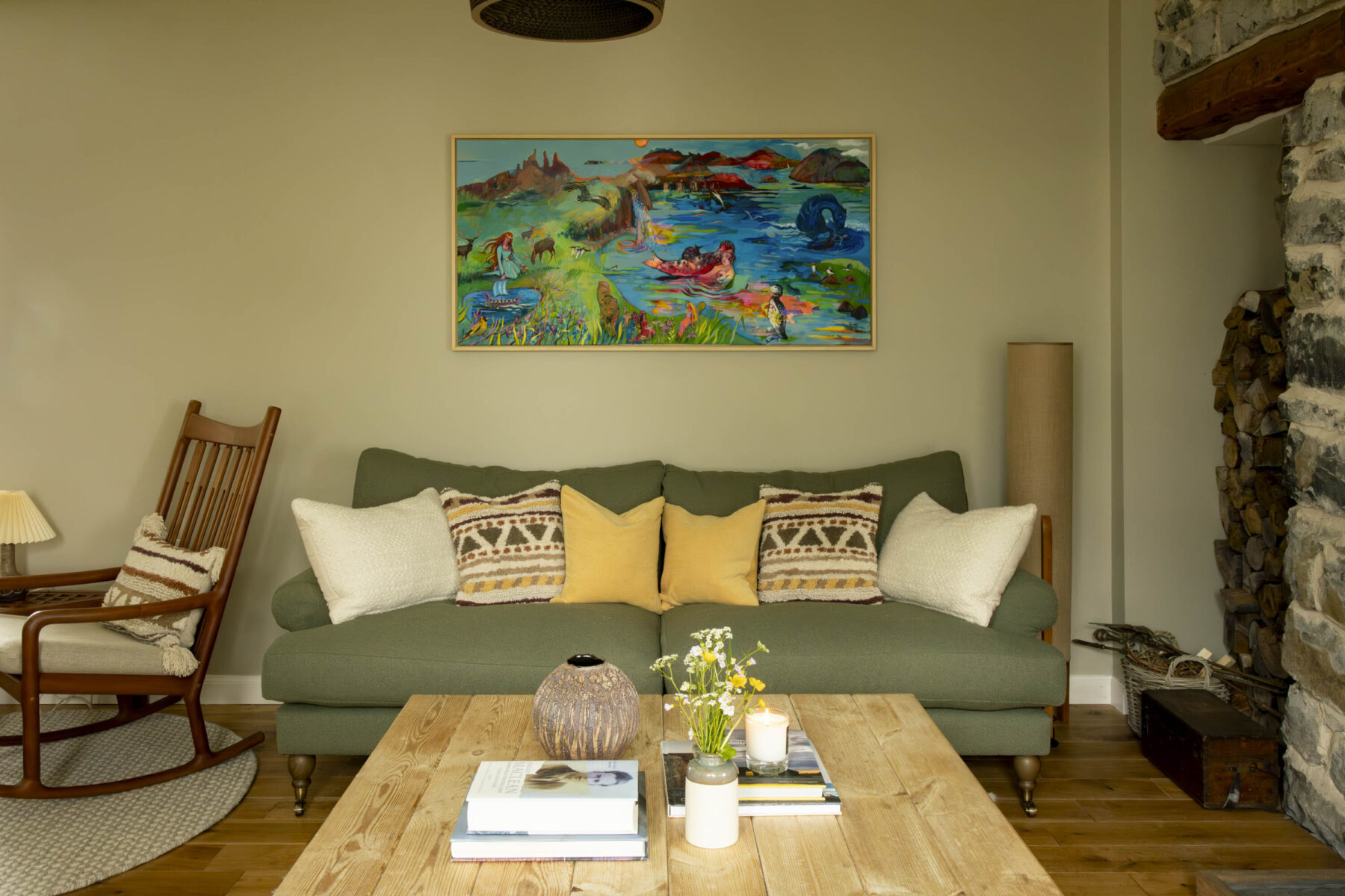 Folkore of Skye - a painting by Scottish artist Rosemary Beaton above a green upholstered sofa in the sitting room at Croft House cottage, Skye.