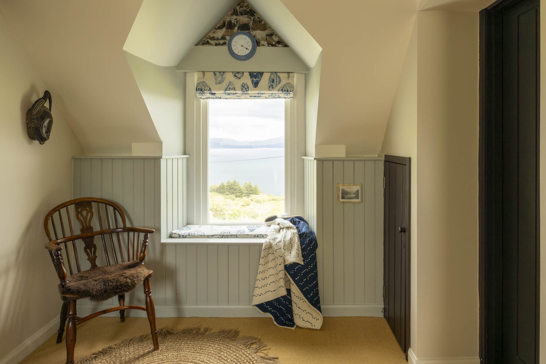 On the landing with a view of the sea at Mint Croft, Skye. Tongue and groove panelling, antique wooden windsor chair.