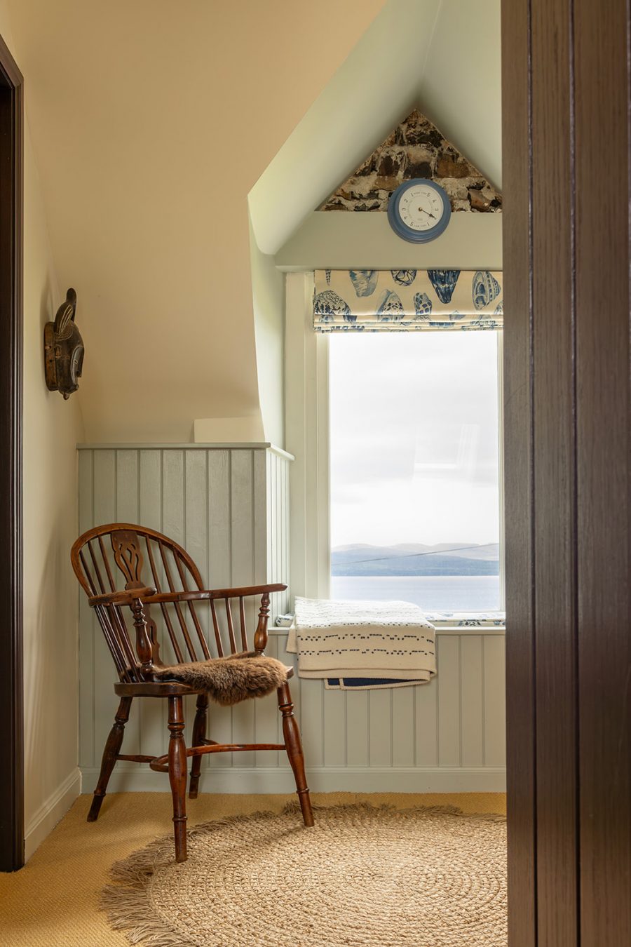 On the landing with dormer window at the Croft House cottage at Geary, Skye, Scotland. A view to the sea, a stick back windsor chair.