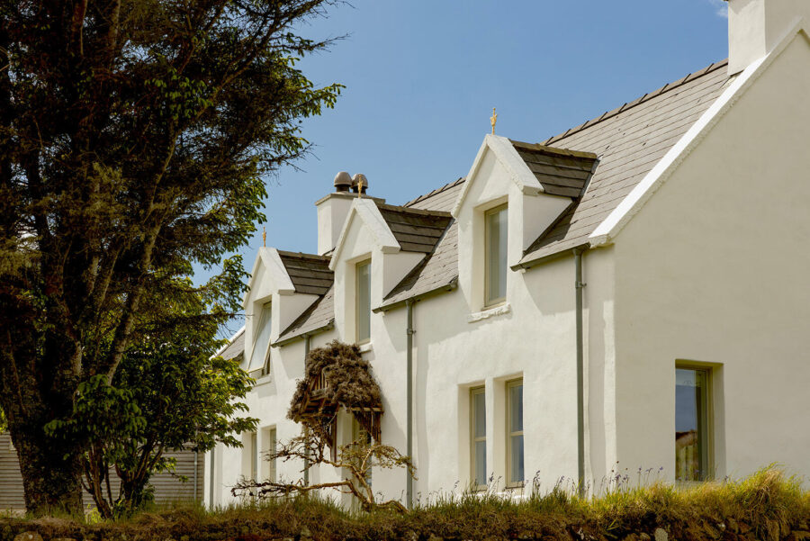 The Croft House at Mint Croft Skye, a traditional Scottish Highlands cottage. Whitewashed stone with two storeys, three dormer windows and a pitched slate roof.