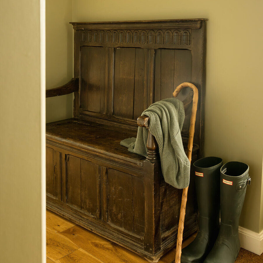 Antique settle with walking stick and wellies in the entrance hall of the Croft House at Mint Croft Skye