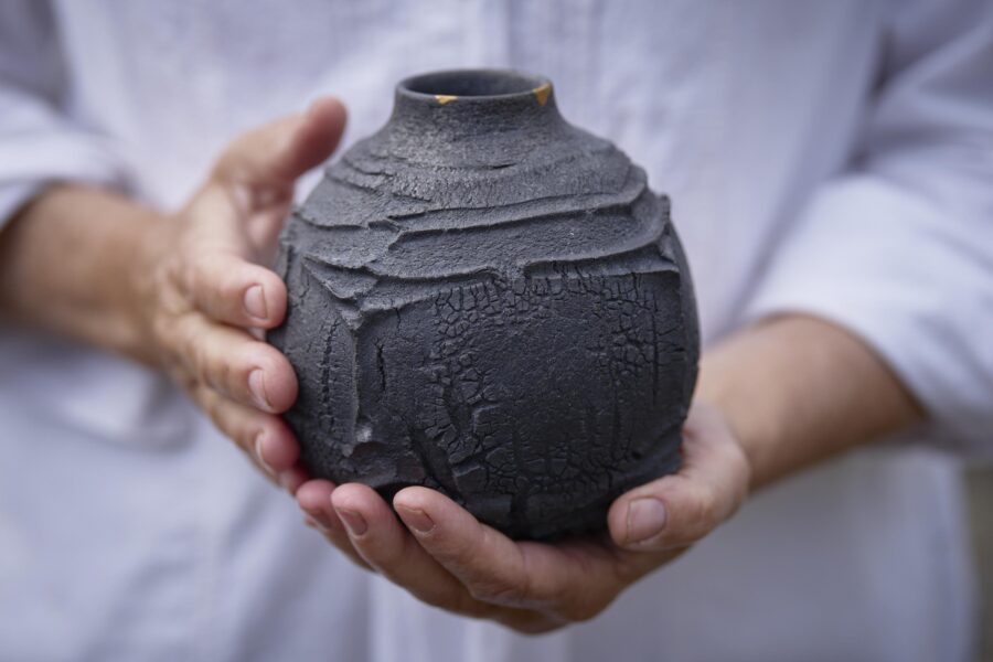 A ceramic flask with rustic, cracked and textured surface and almost black, matte glaze by Skye artist Patricia Shone